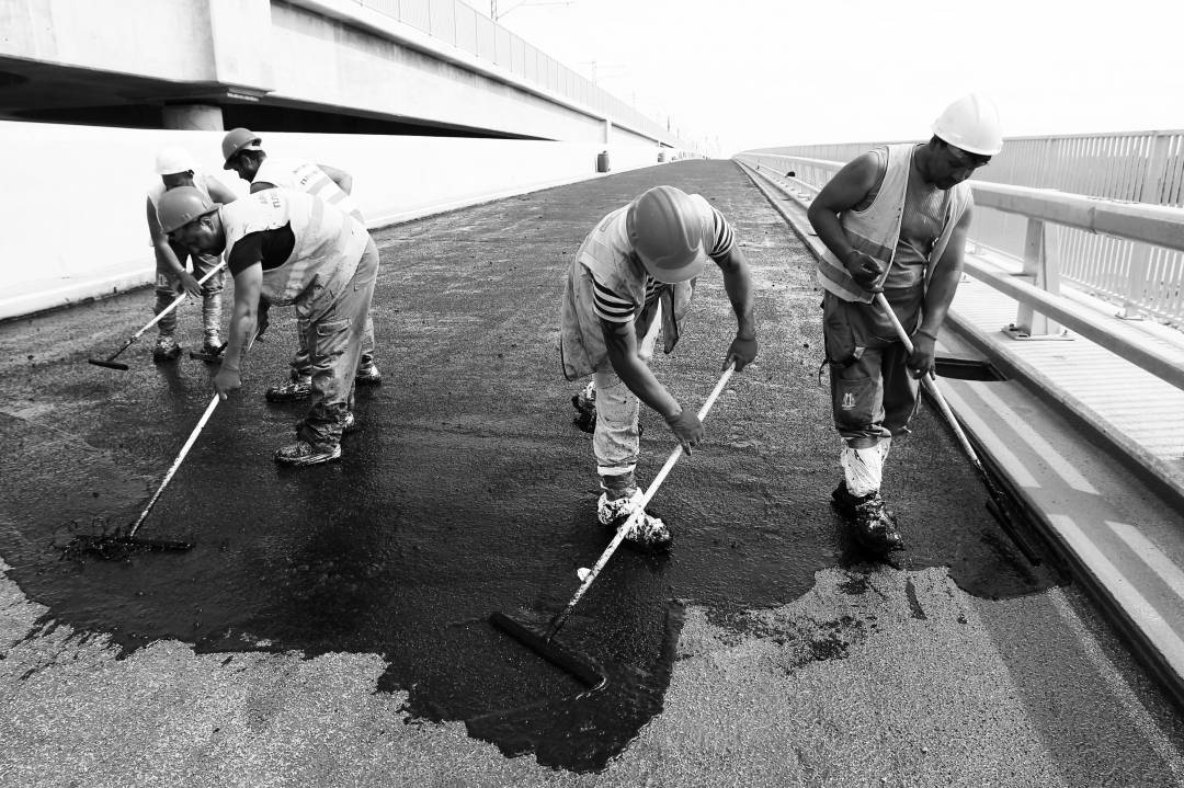 Workers pave a road on a newly constructed bridge over the Danube River, that links Calafat in Romania to Vidin in Bulgaria